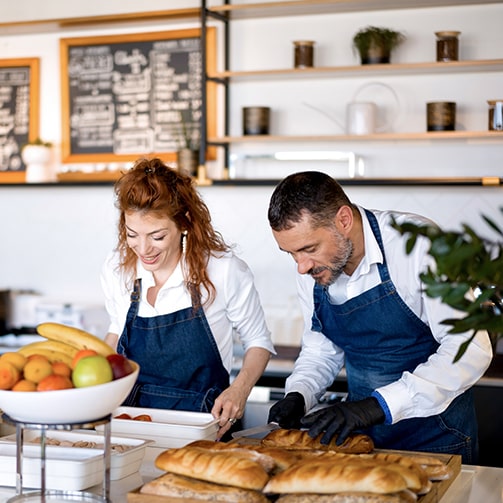 Two café employees preparing food for customers.